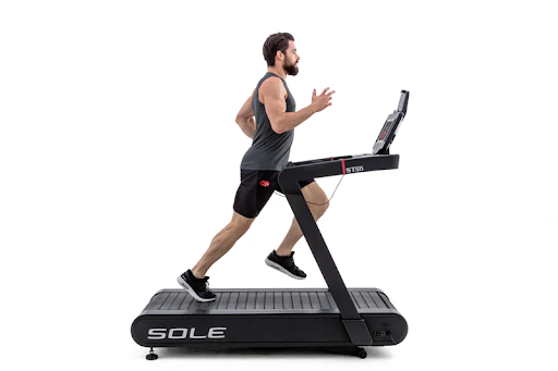 Man running on SOLE ST90 treadmill, engaged in high-intensity workout.