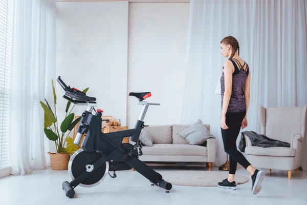 Woman in workout clothes stands next to a SOLE exercise bike in living room